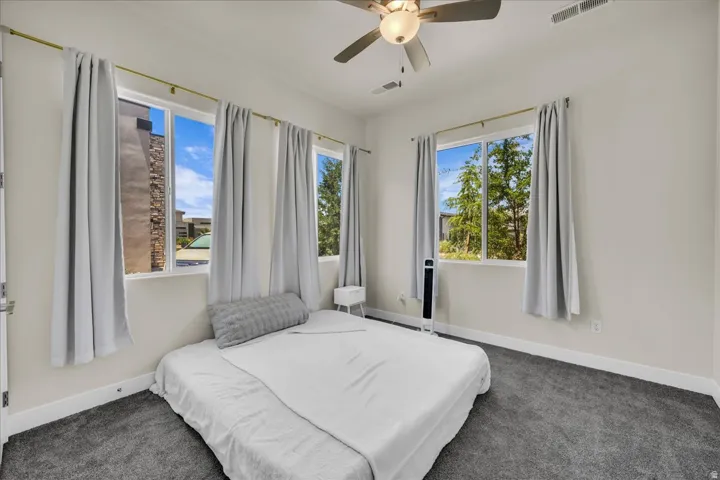 Neutral tone walls with white trim, dark gray carpeting, and multiple windows