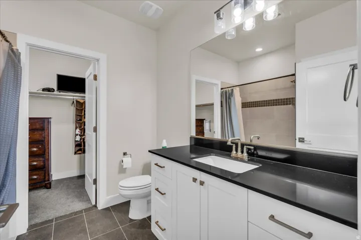 Bathroom featuring a dark countertop vanity with dual-handle faucet, white cabinetry, and an integrated rectangular sink