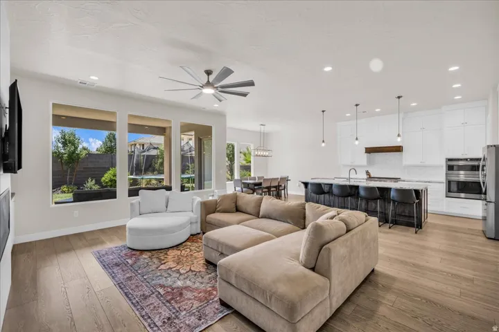 Open-concept living area featuring wide plank wood-finish flooring, recessed lighting, and a modern ceiling fan
