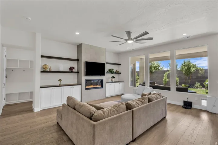Spacious living area featuring wood-finish flooring, a linear fireplace with a stone-look surround, and recessed lighting