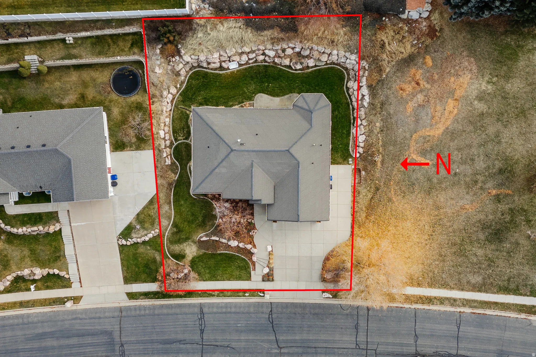 Aerial view showcasing a property with a grey roof and a concrete driveway