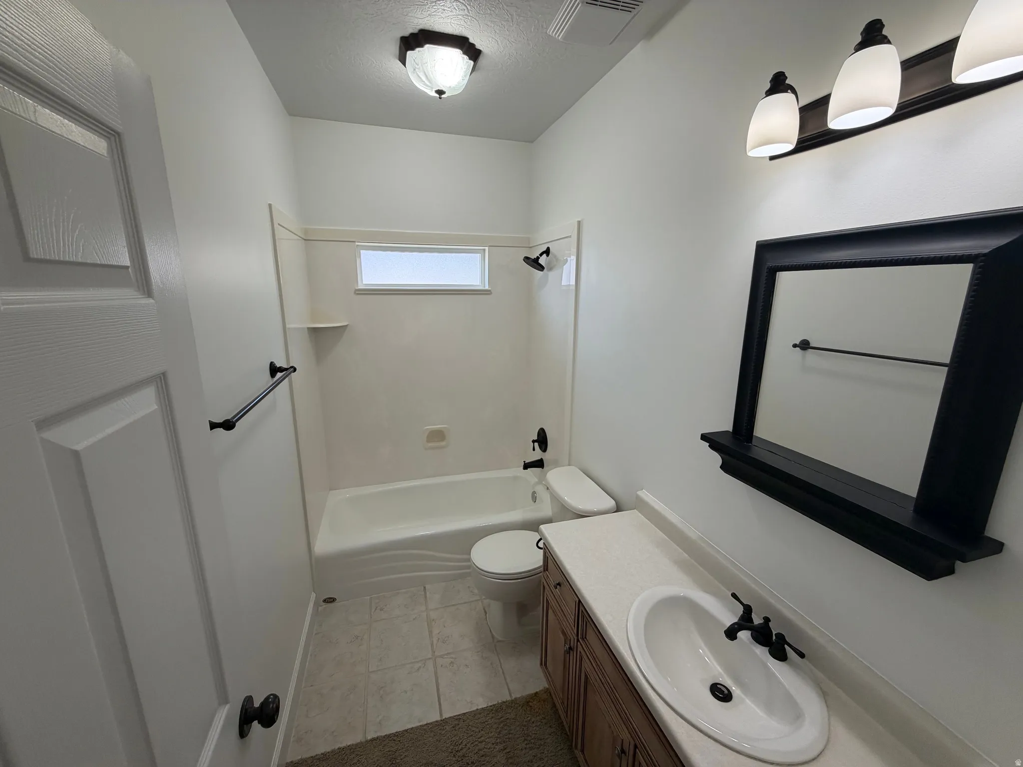 Bathroom featuring a vanity with a white oval sink, dark wood-finish cabinetry, and a light-toned countertop
