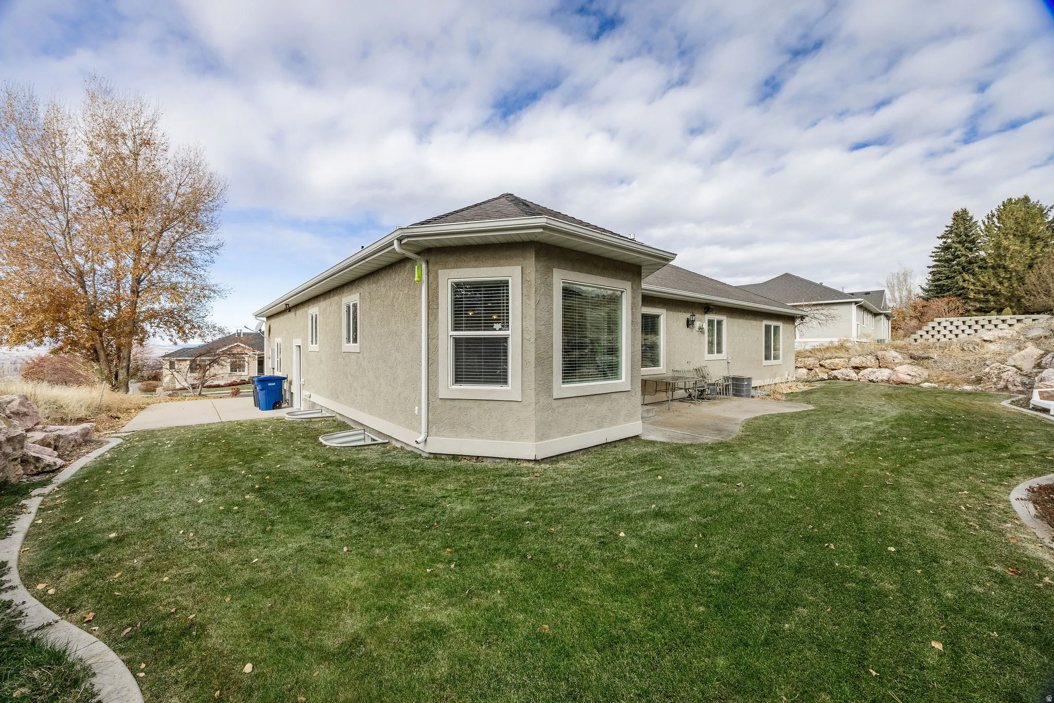 Rear exterior featuring a stucco facade, multiple windows with white trim, and a patio area