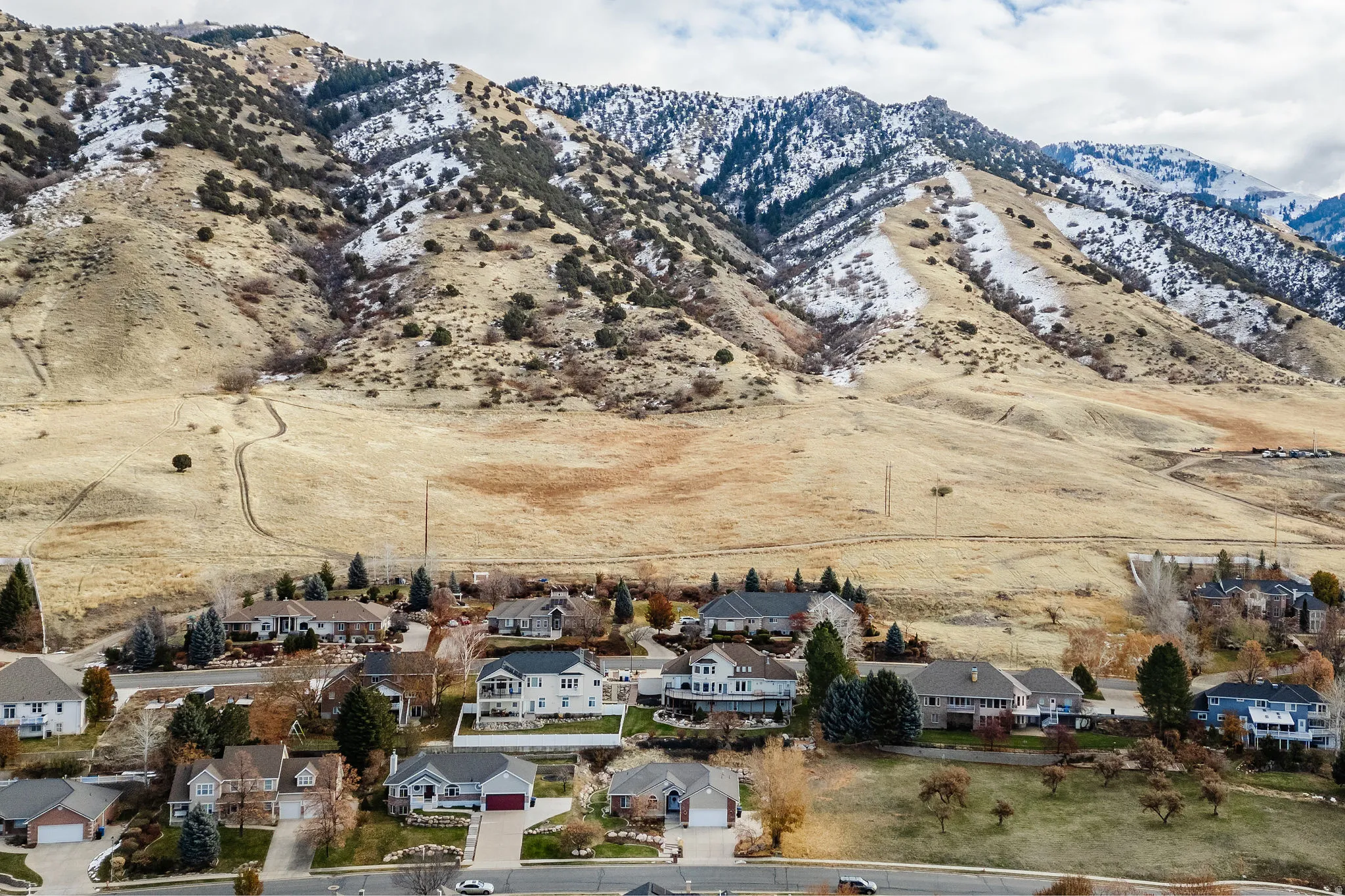 Aerial perspective featuring a residential area nestled against a prominent mountain range with snow-dusted peaks