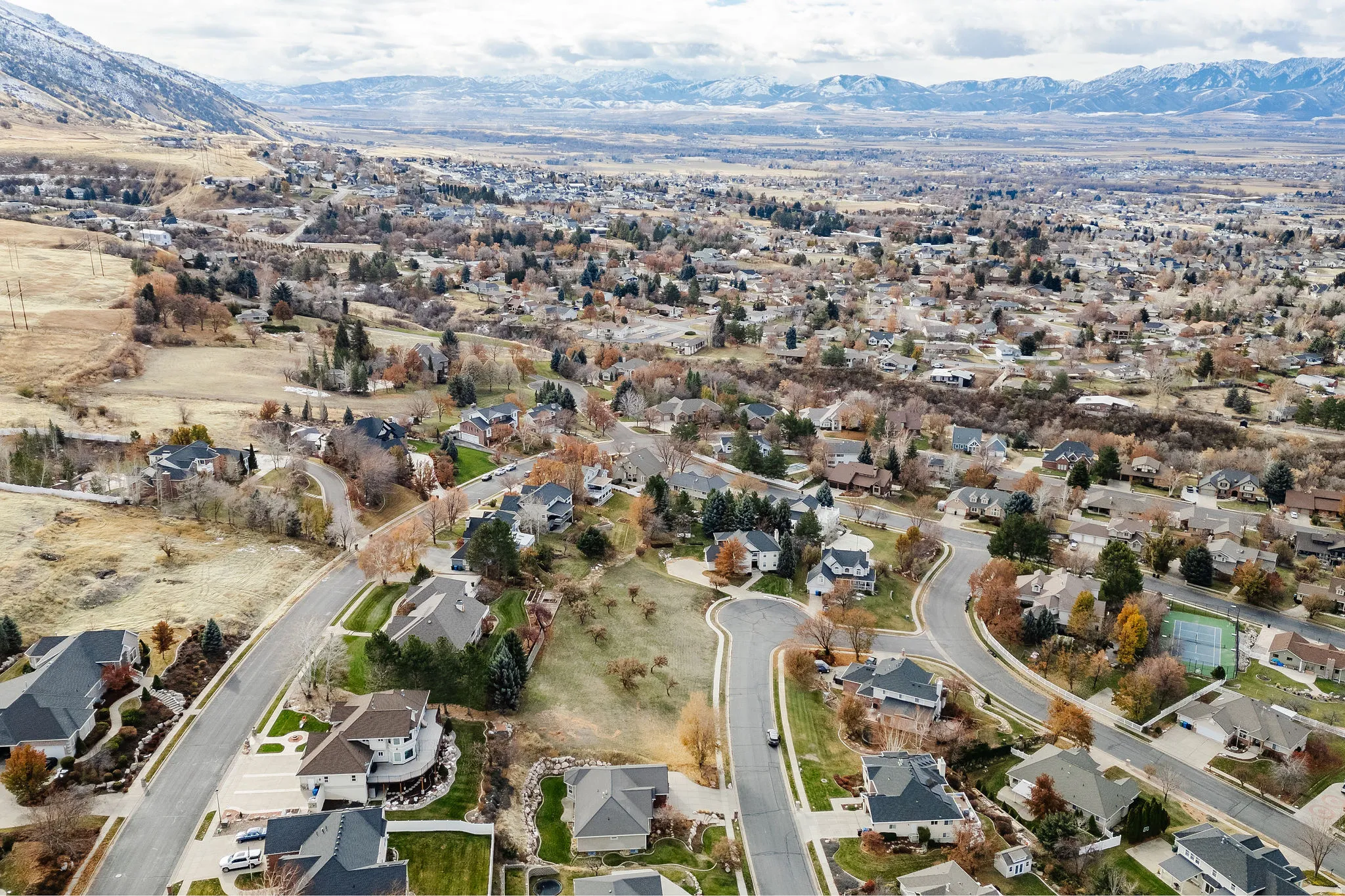 Residential landscape featuring numerous homes, expansive natural terrain, and distant snow-capped mountains