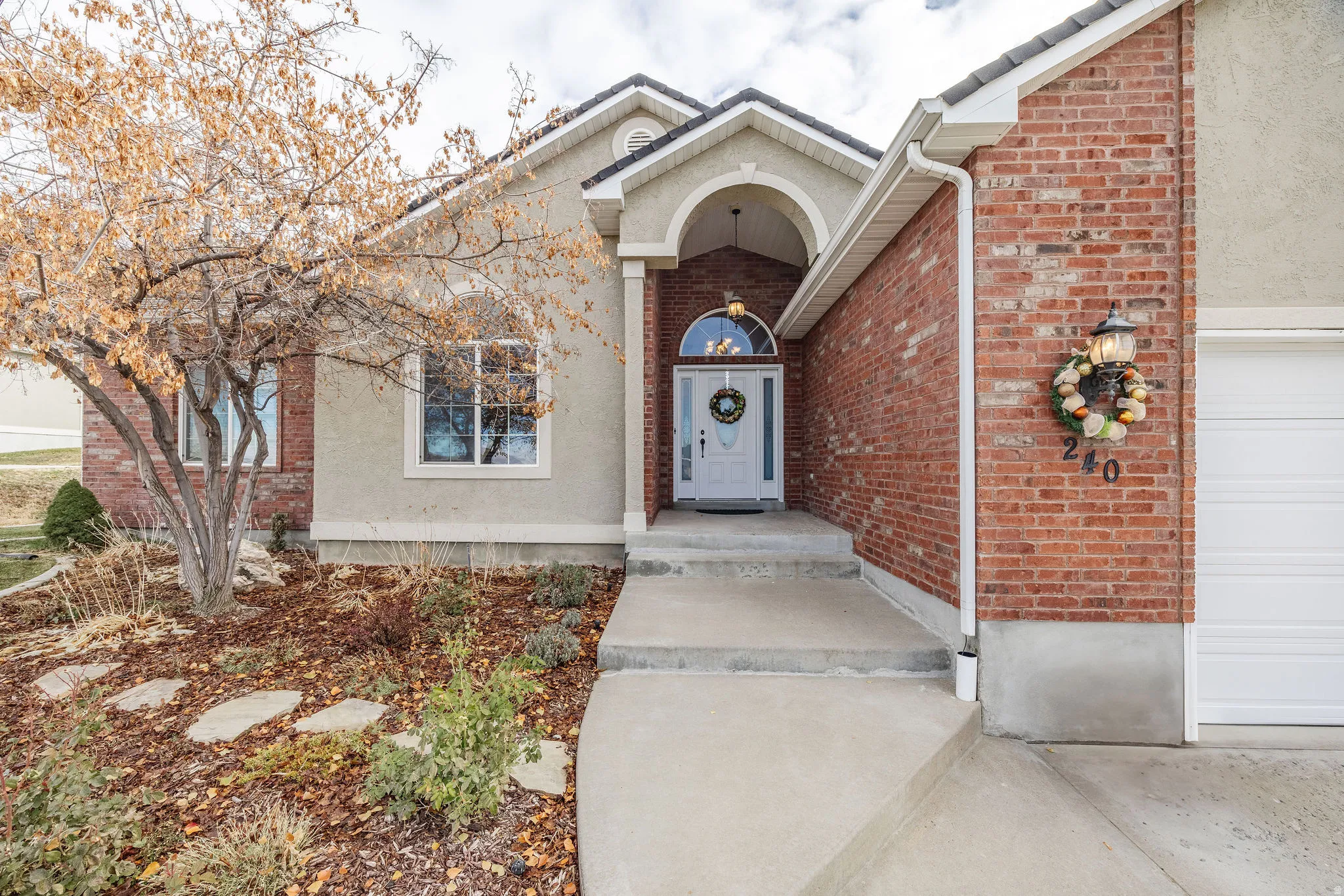 Entryway featuring an arched portico, a white front door with an arched transom, and a concrete pathway
