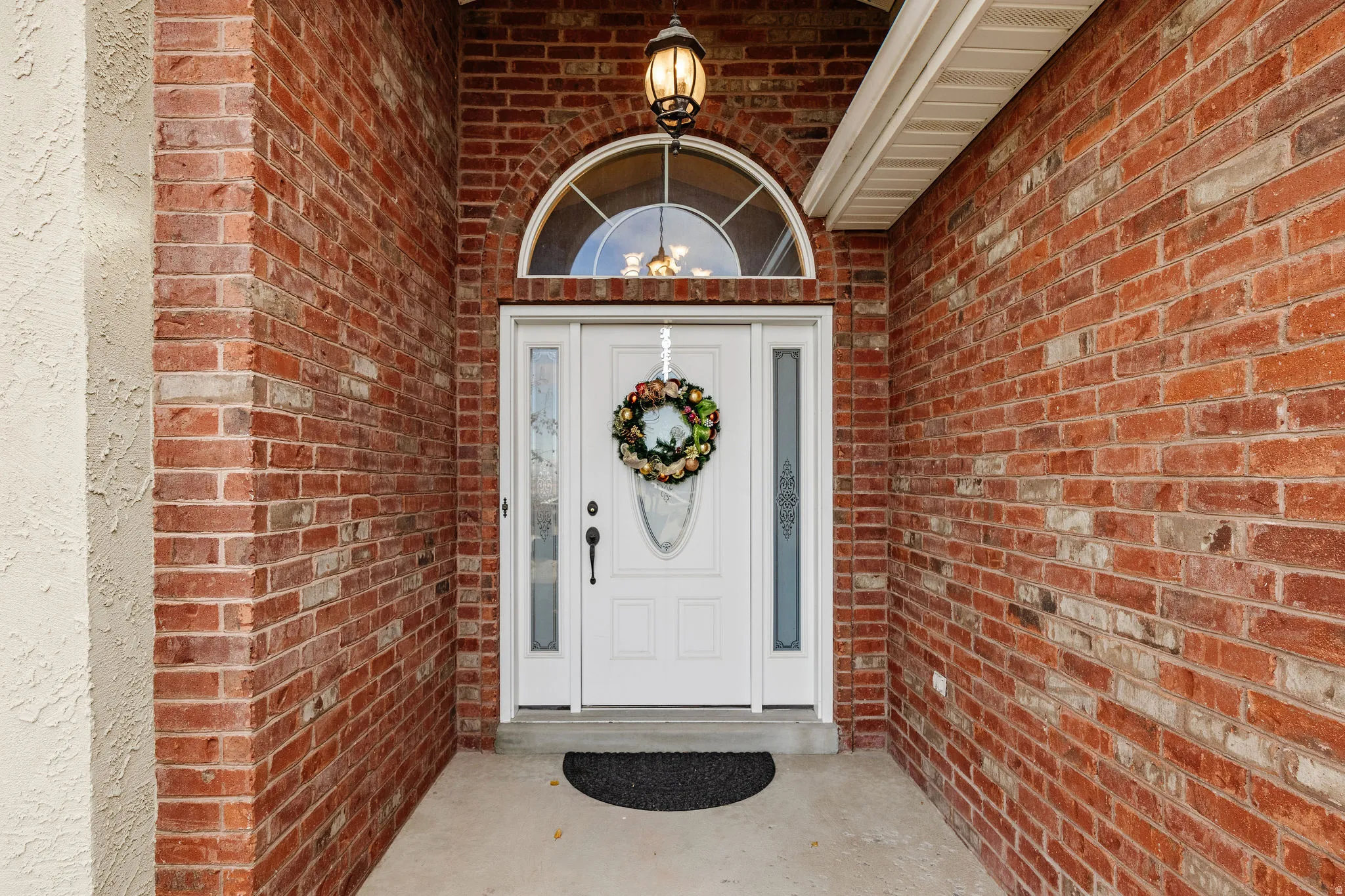 Entryway featuring a white door with sidelights, an arched transom window, and a decorative overhead light fixture