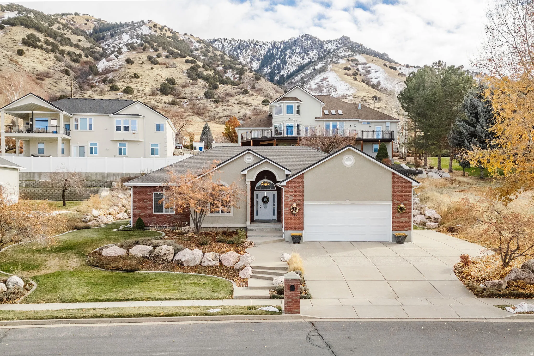 Ranch-style exterior featuring a two-car garage, brick and stucco facade, and a concrete driveway