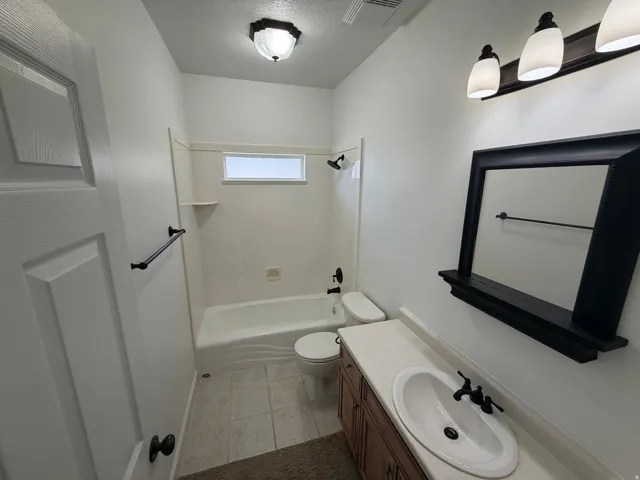 Bathroom featuring a vanity with a white oval sink, dark wood-finish cabinetry, and a light-toned countertop