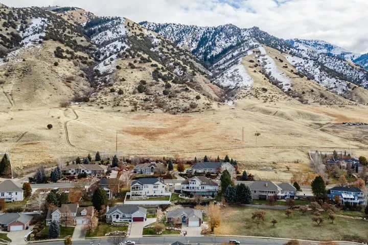 Aerial perspective featuring a residential area nestled against a prominent mountain range with snow-dusted peaks