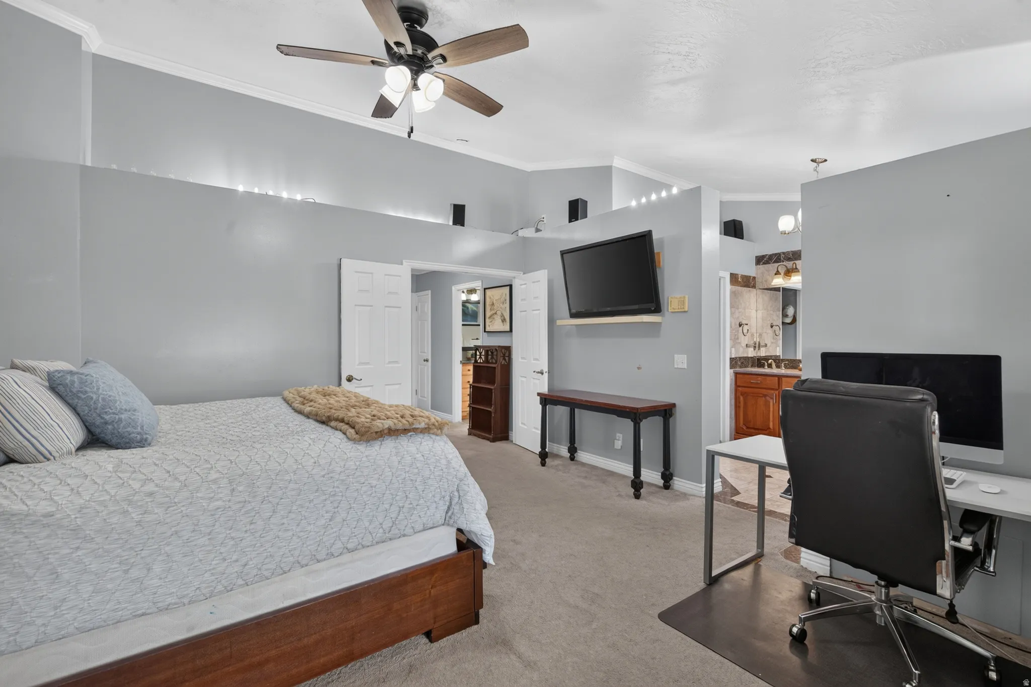 Spacious bedroom featuring light gray walls, crown molding, and a ceiling fan