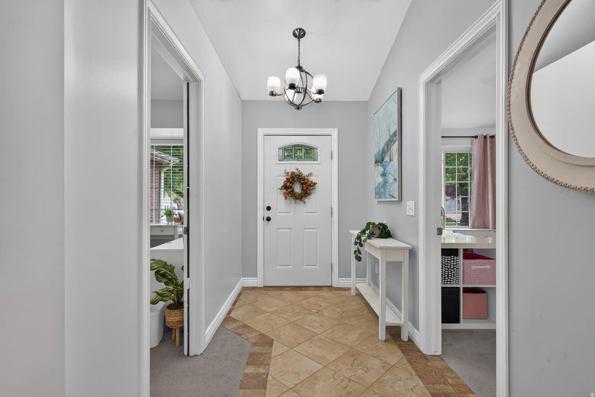 Entryway featuring a decorative chandelier, white door with glass insert, and patterned tile flooring
