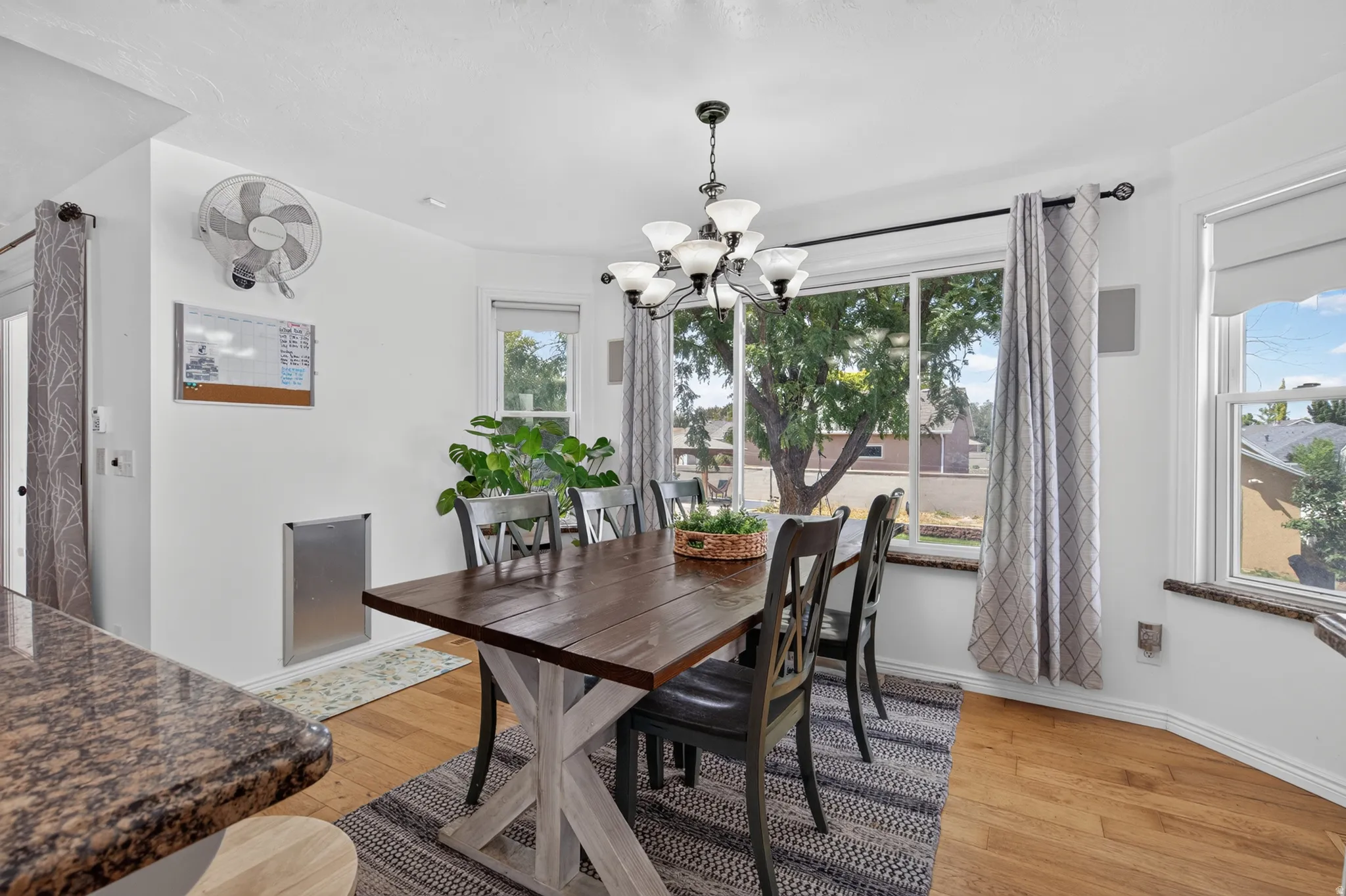 Dining area featuring wood-finish flooring, a contemporary chandelier, and large windows
