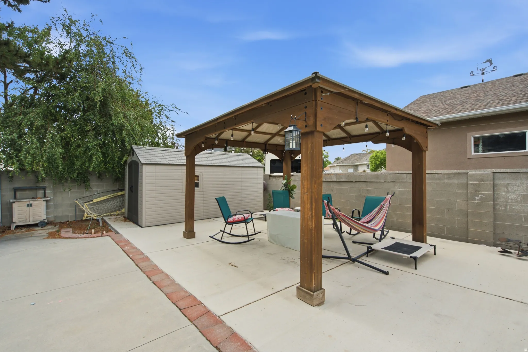 Paved patio with a wood pergola structure featuring string lighting and a central lantern