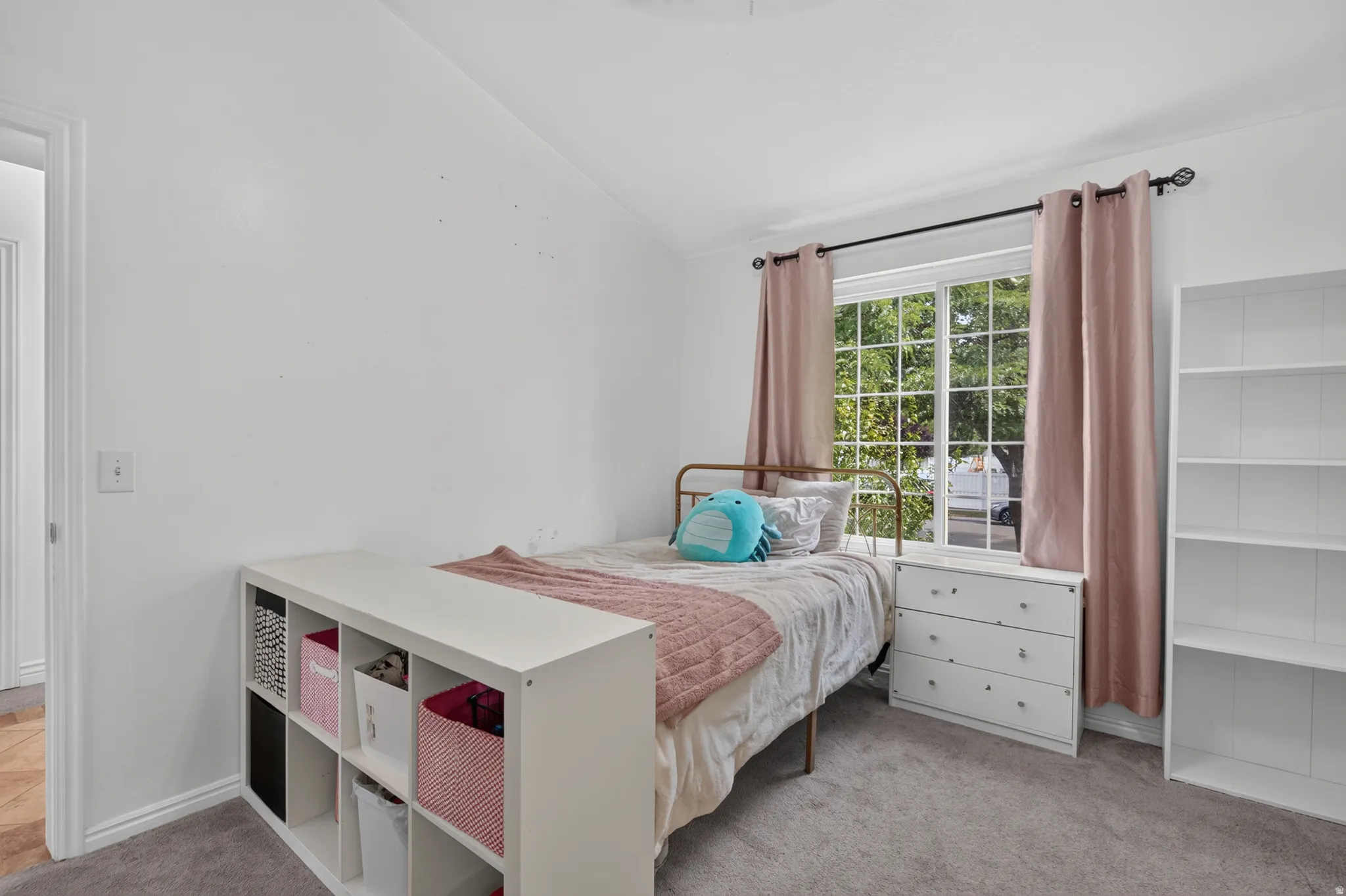 Bedroom featuring a large grid window, dark curtain rod, light pink curtains, and carpet flooring