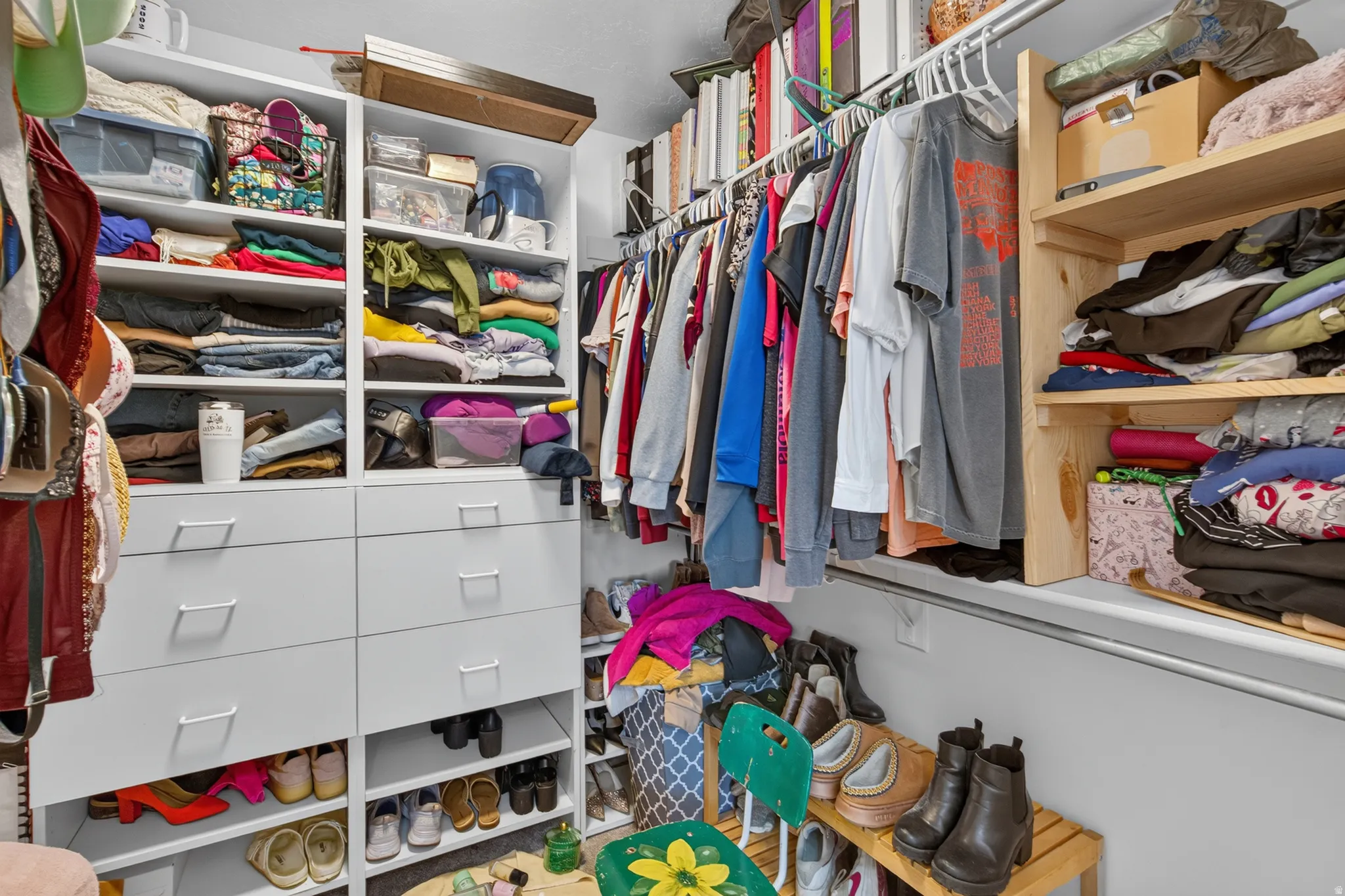 Custom closet system featuring white built-in cabinetry, integrated drawers with modern pulls, open shelving, and garment hanging rods