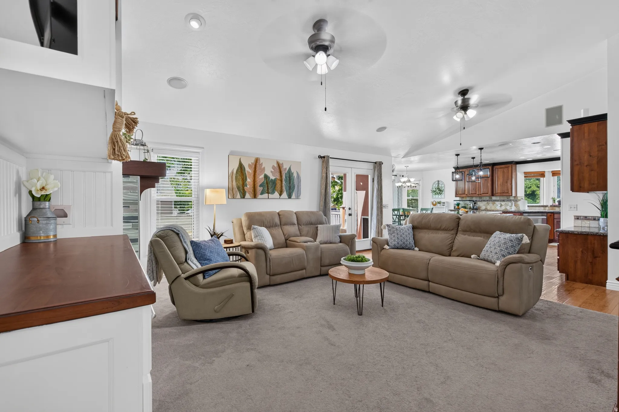 Spacious living area featuring vaulted ceilings with ceiling fans, recessed lighting, and soft gray carpeting