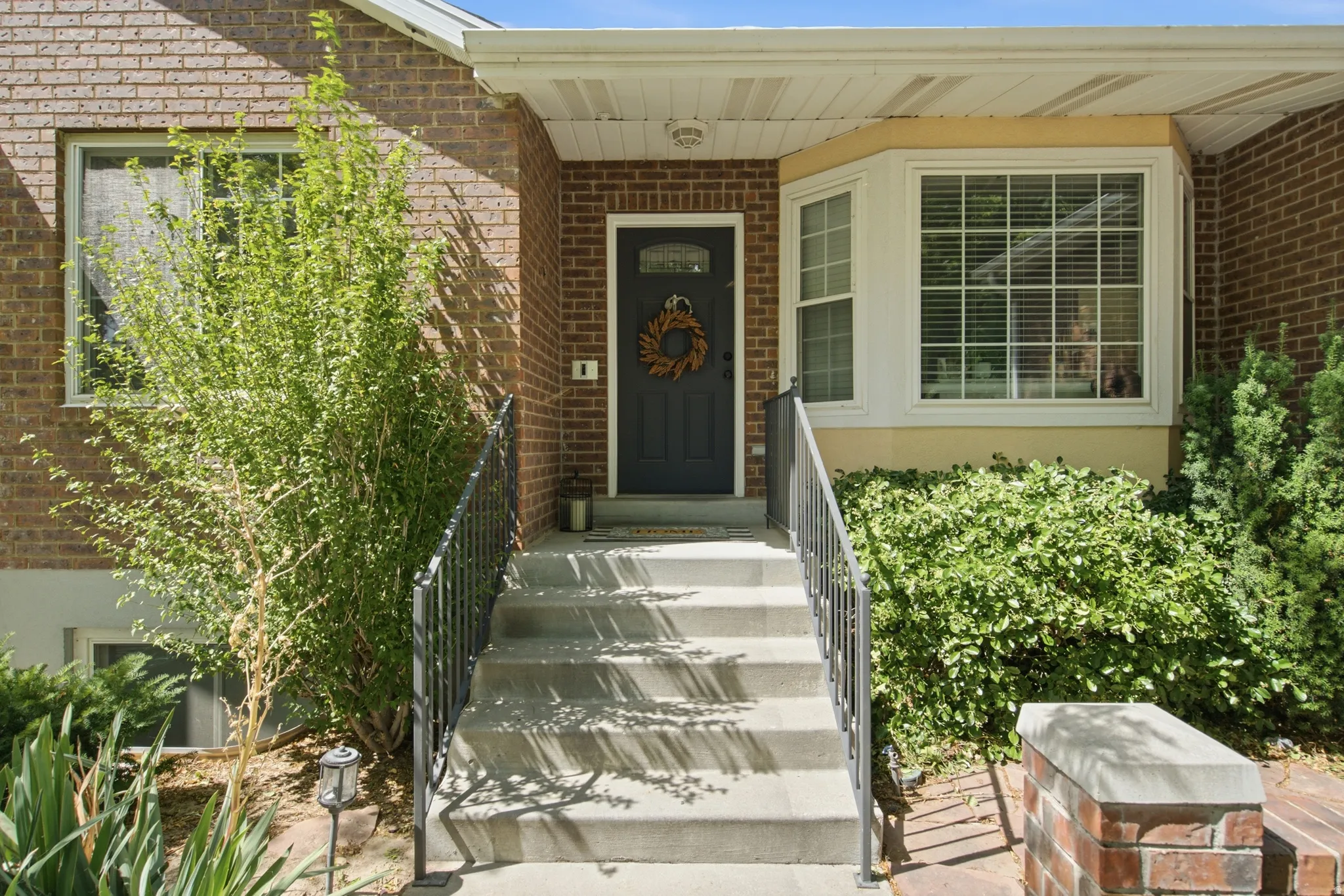 Brick facade entry with concrete steps and wrought iron railings