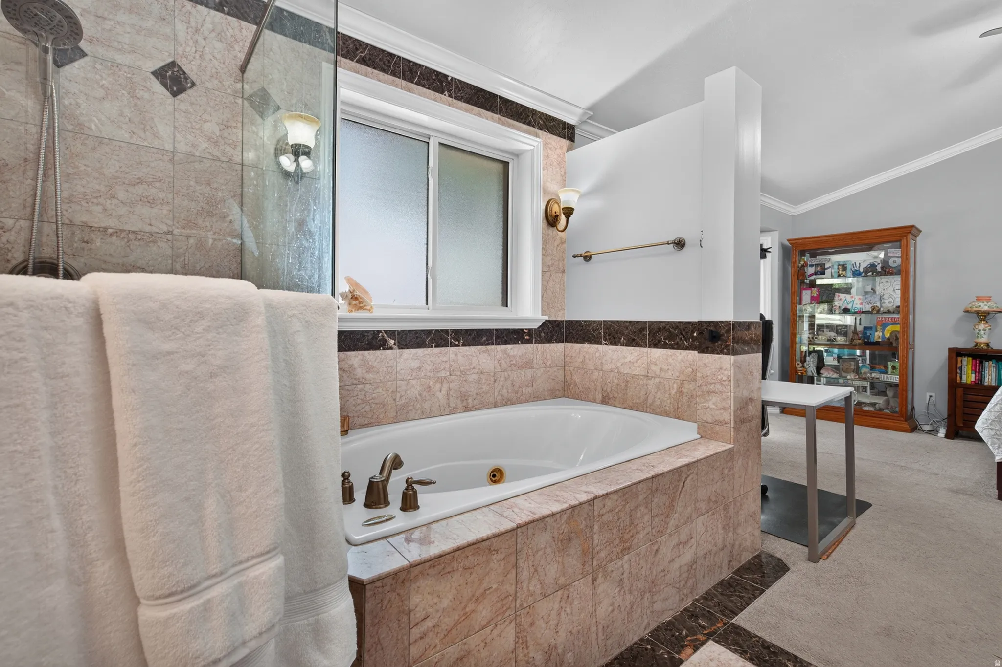 Tiled bathroom featuring a built-in soaking tub with brass fixtures, a shower enclosure with a rainfall showerhead, and a frosted window