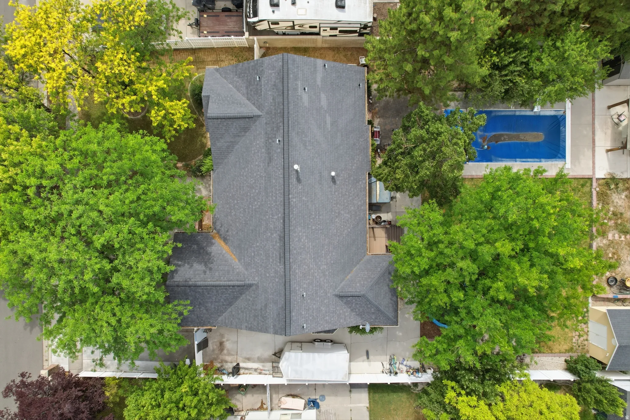 Property with a dark shingle roof and surrounding mature trees