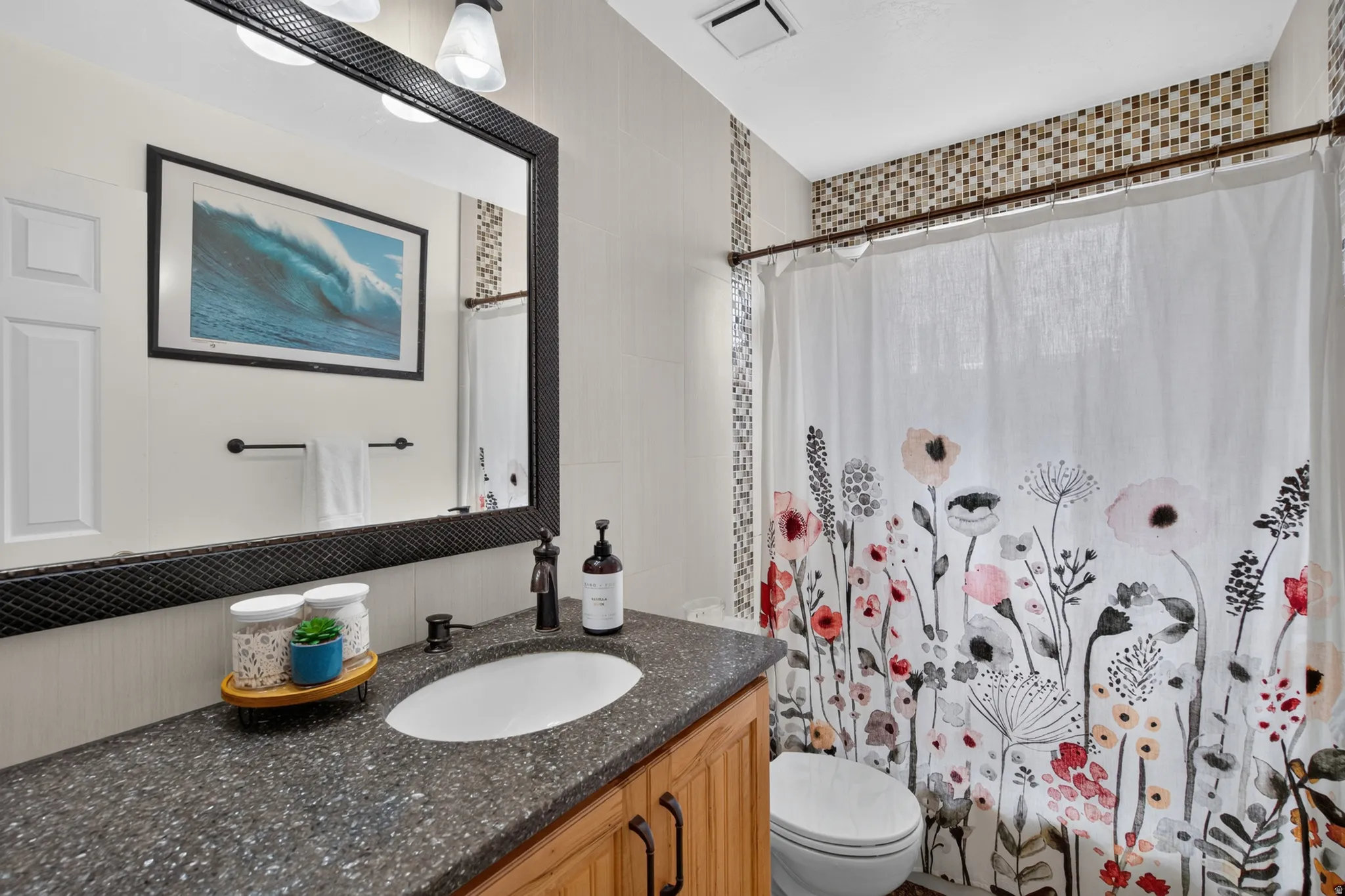 Bathroom featuring a vanity with wood-finish cabinetry, a dark speckled countertop, and an undermount sink