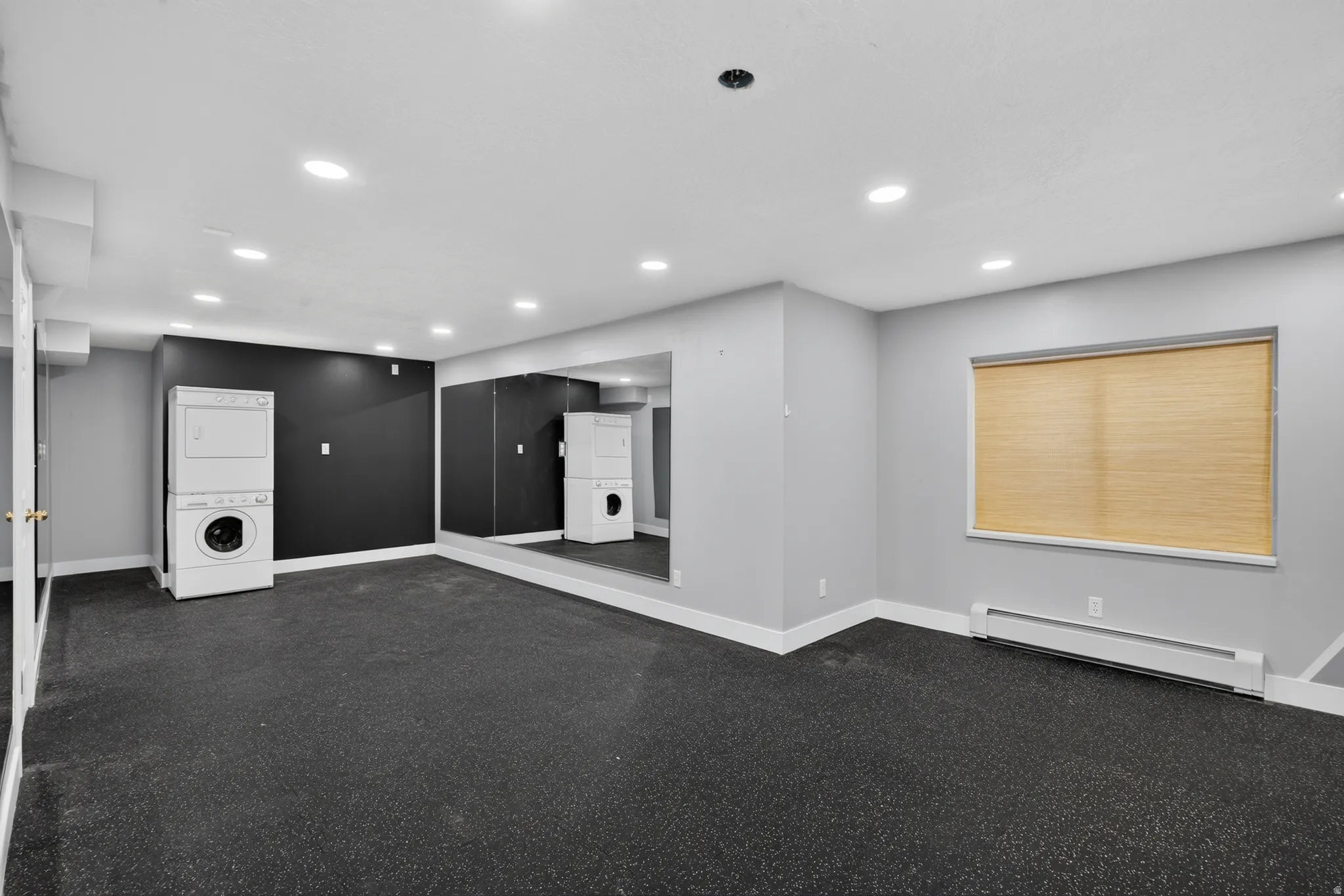 Spacious room featuring black rubber flooring, light gray walls, and white baseboards