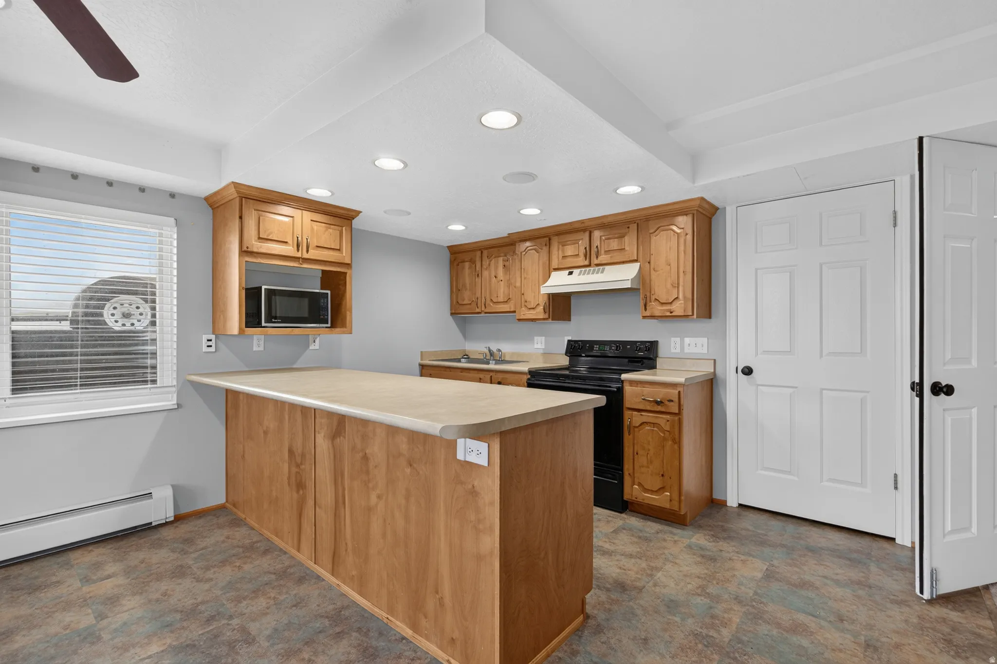 Kitchen featuring wood-finish cabinetry, a central island with countertop, and recessed lighting