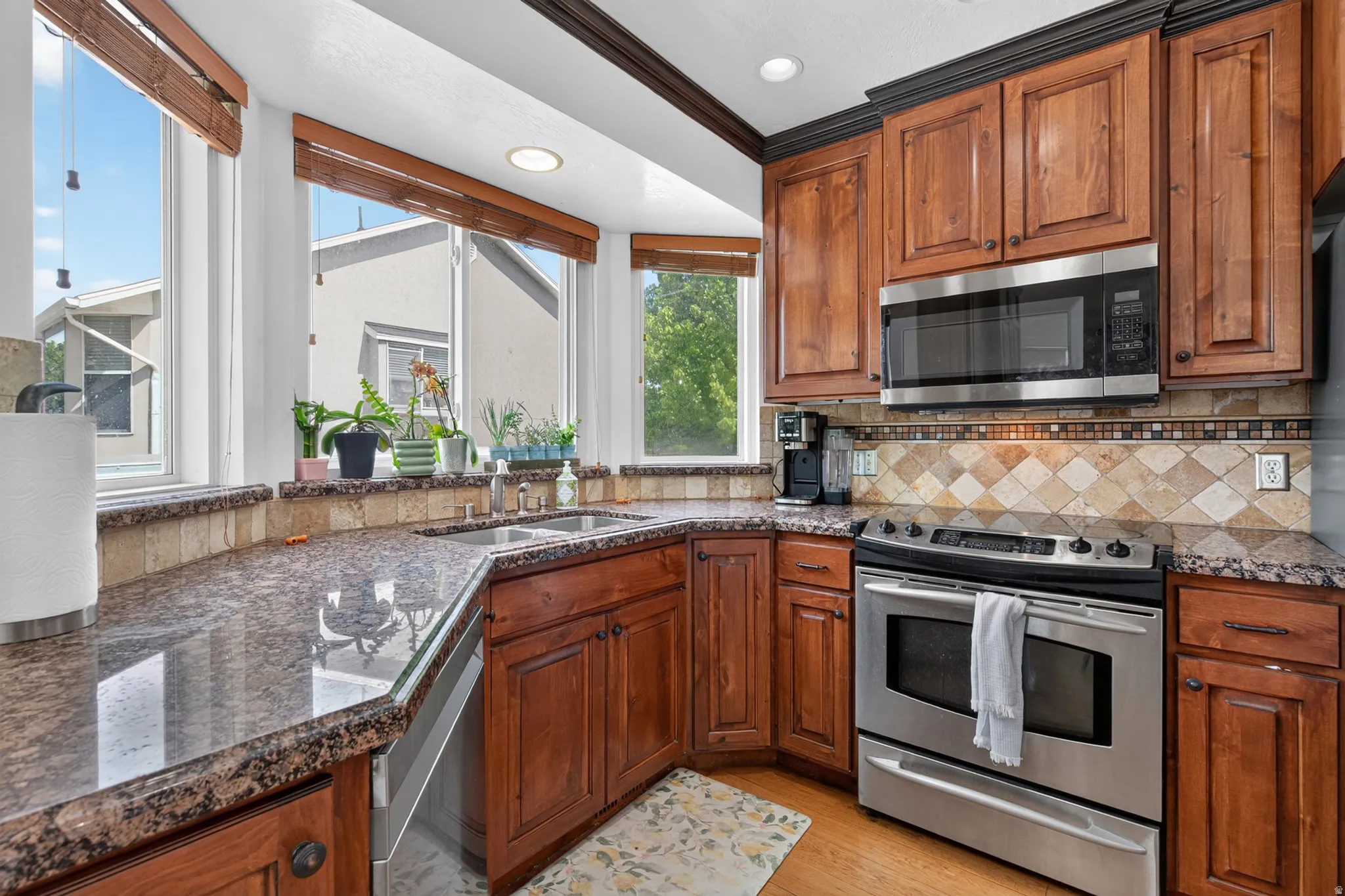 Kitchen featuring rich wood cabinetry, stainless steel appliances, speckled stone countertops, and a decorative tile backsplash