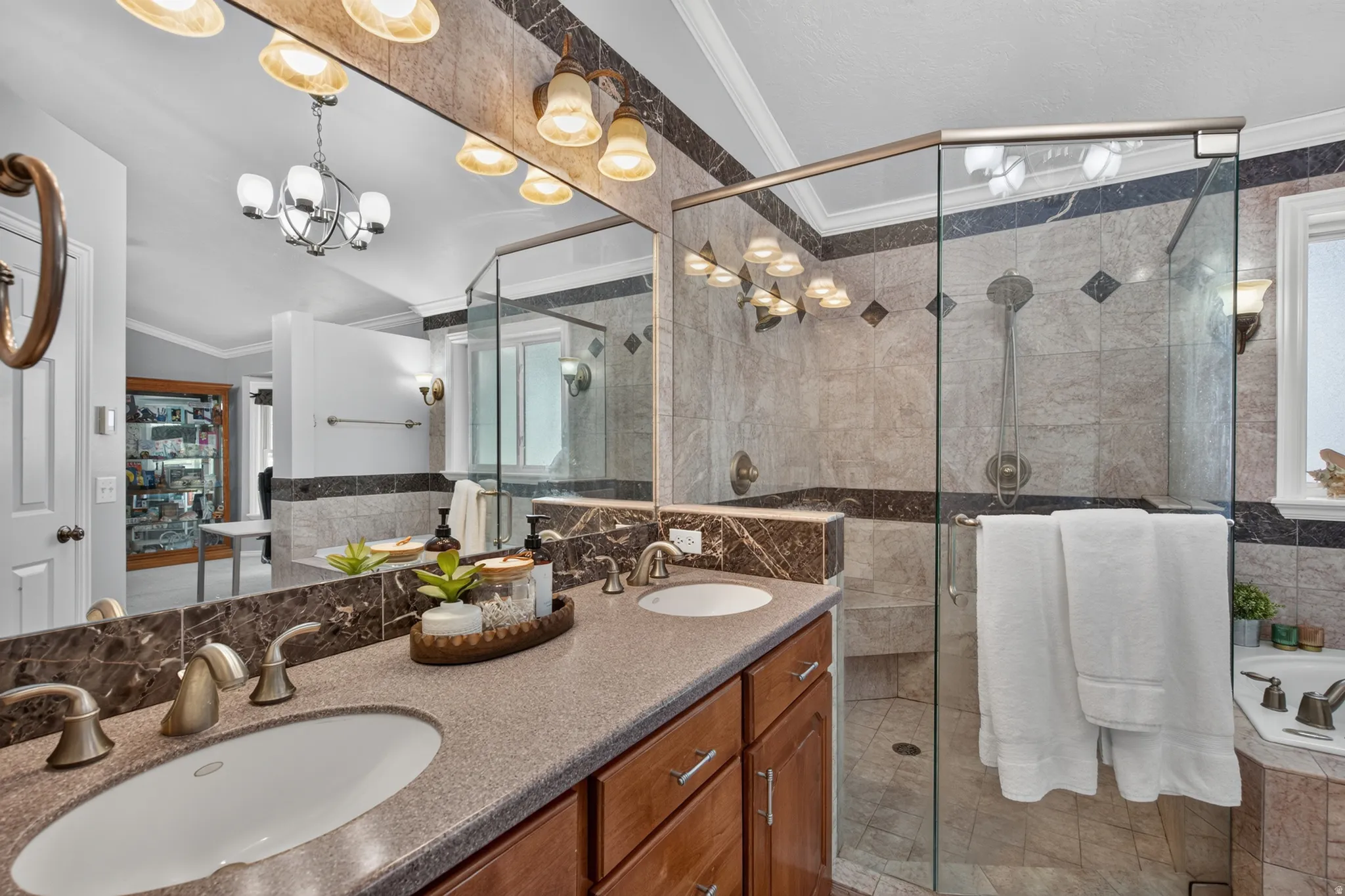Bathroom featuring a dual vanity with undermount sinks, bronze-finish faucets, a glass-enclosed shower, and a built-in tub