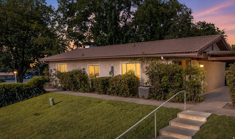 Exterior featuring a tiled roof, stucco siding, mature landscaping, and an inviting entry with concrete steps and a handrail