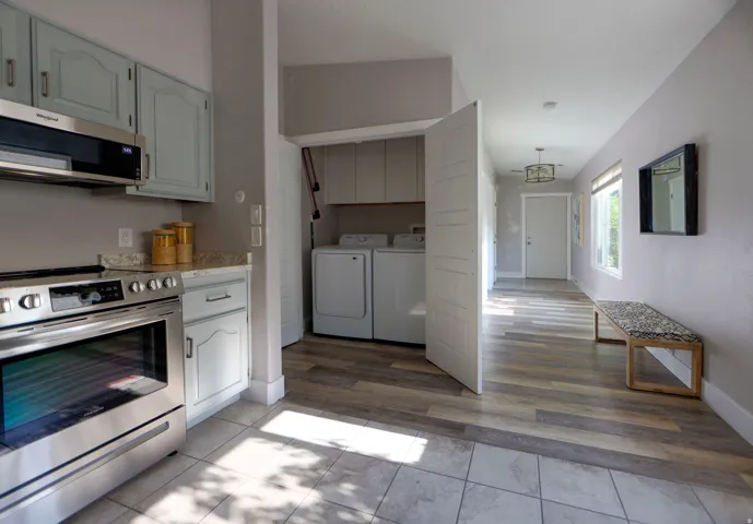 Stainless steel range with matching microwave hood, light blue cabinetry, light-toned countertops, and tile flooring in the kitchen