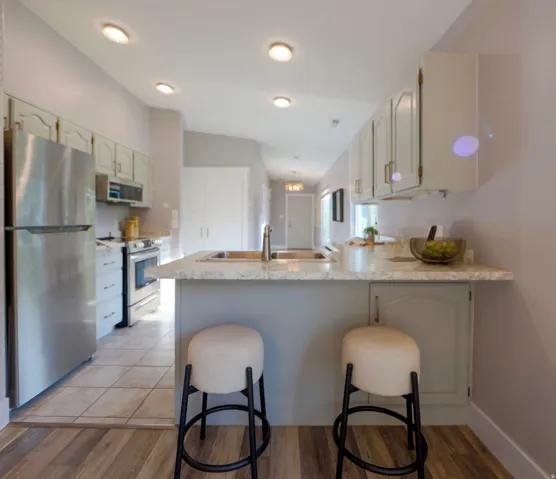 Kitchen with an island featuring a dual-basin sink, light-toned countertop, and integrated cabinetry