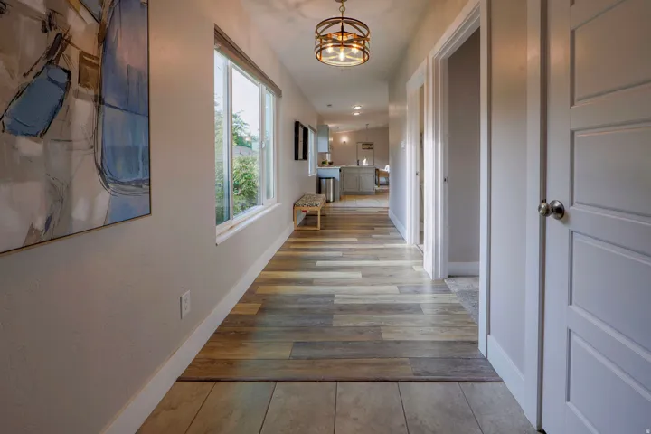 Hallway featuring wood-finish flooring, a contemporary semi-flush mount light fixture, and white panel doors