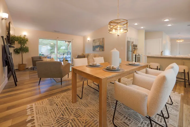 Open-concept living space with wood-finish flooring, recessed lighting, and a modern dining chandelier
