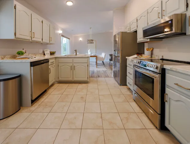Open-concept kitchen featuring extensive cabinetry, stainless steel appliances, and a tile floor