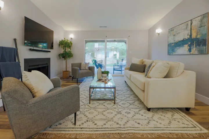 Living area featuring wood-finish flooring, a fireplace with a dark mantel, and recessed lighting