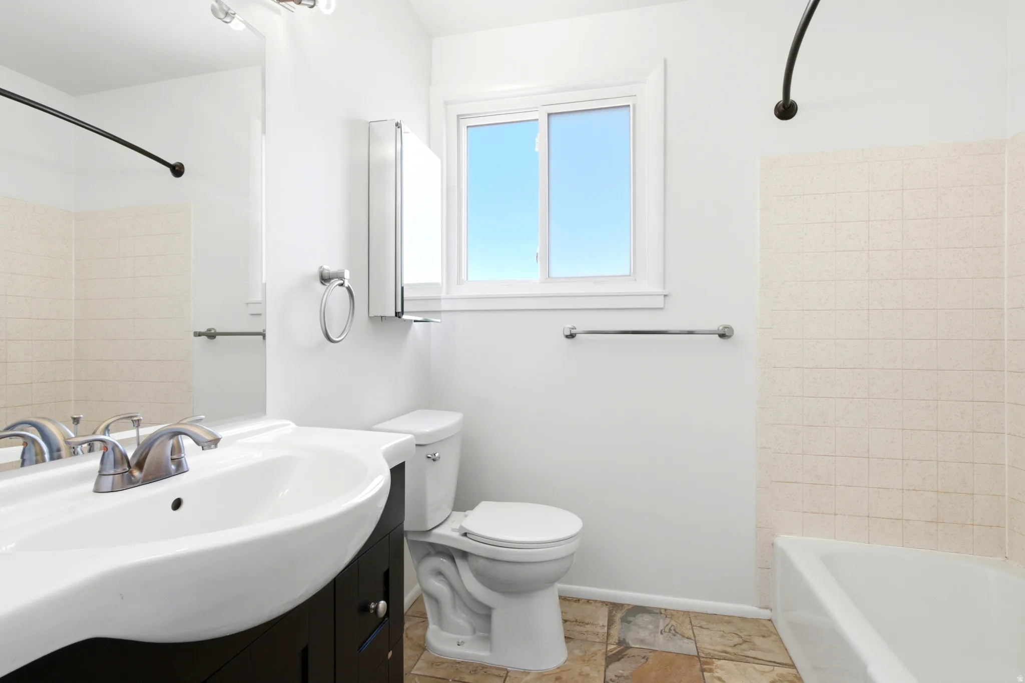 Bathroom featuring a white vanity with integrated sink, chrome faucet, and a large wall-mounted mirror