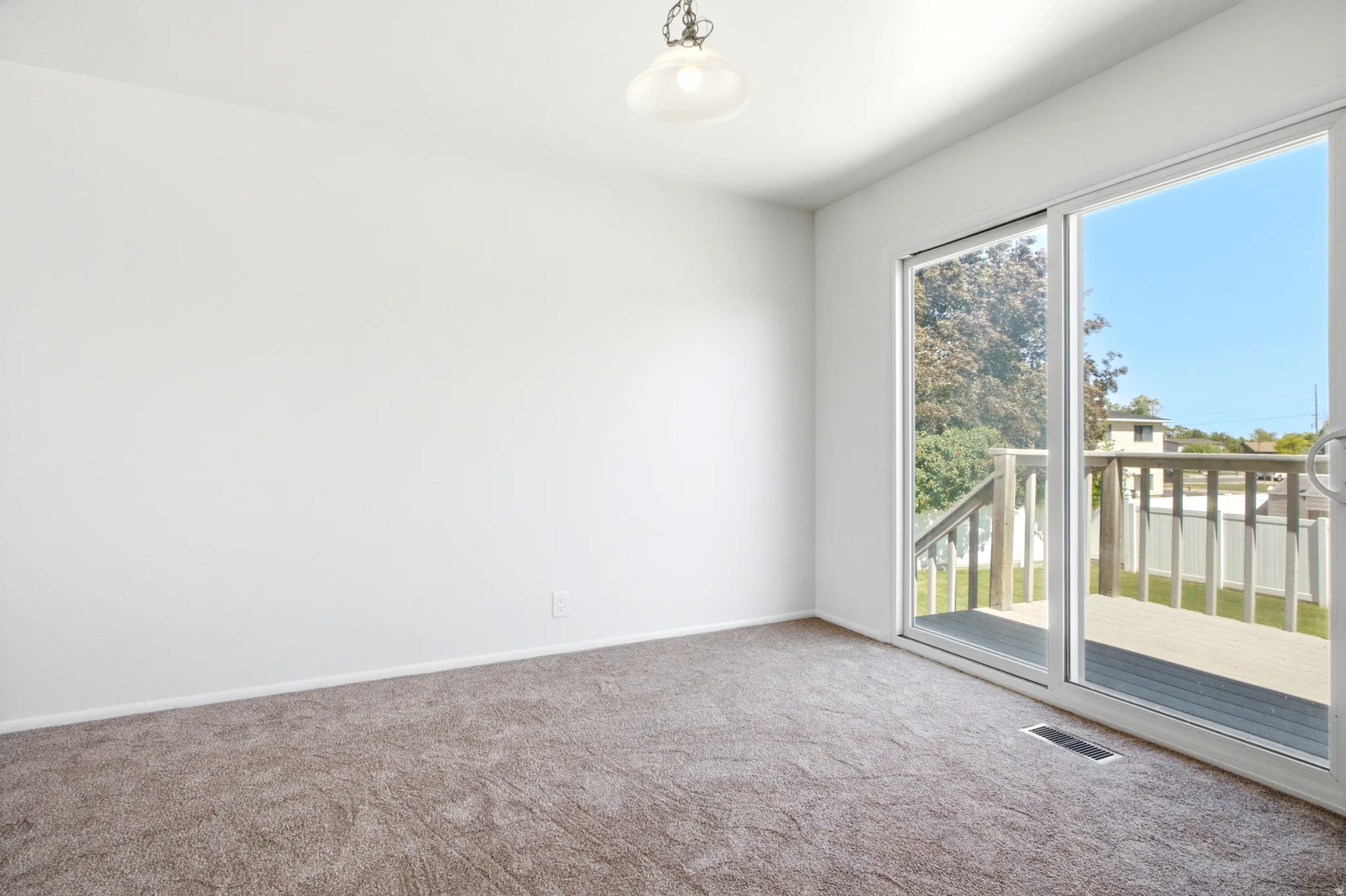 Sliding glass door opening to an exterior wood deck with a slatted railing