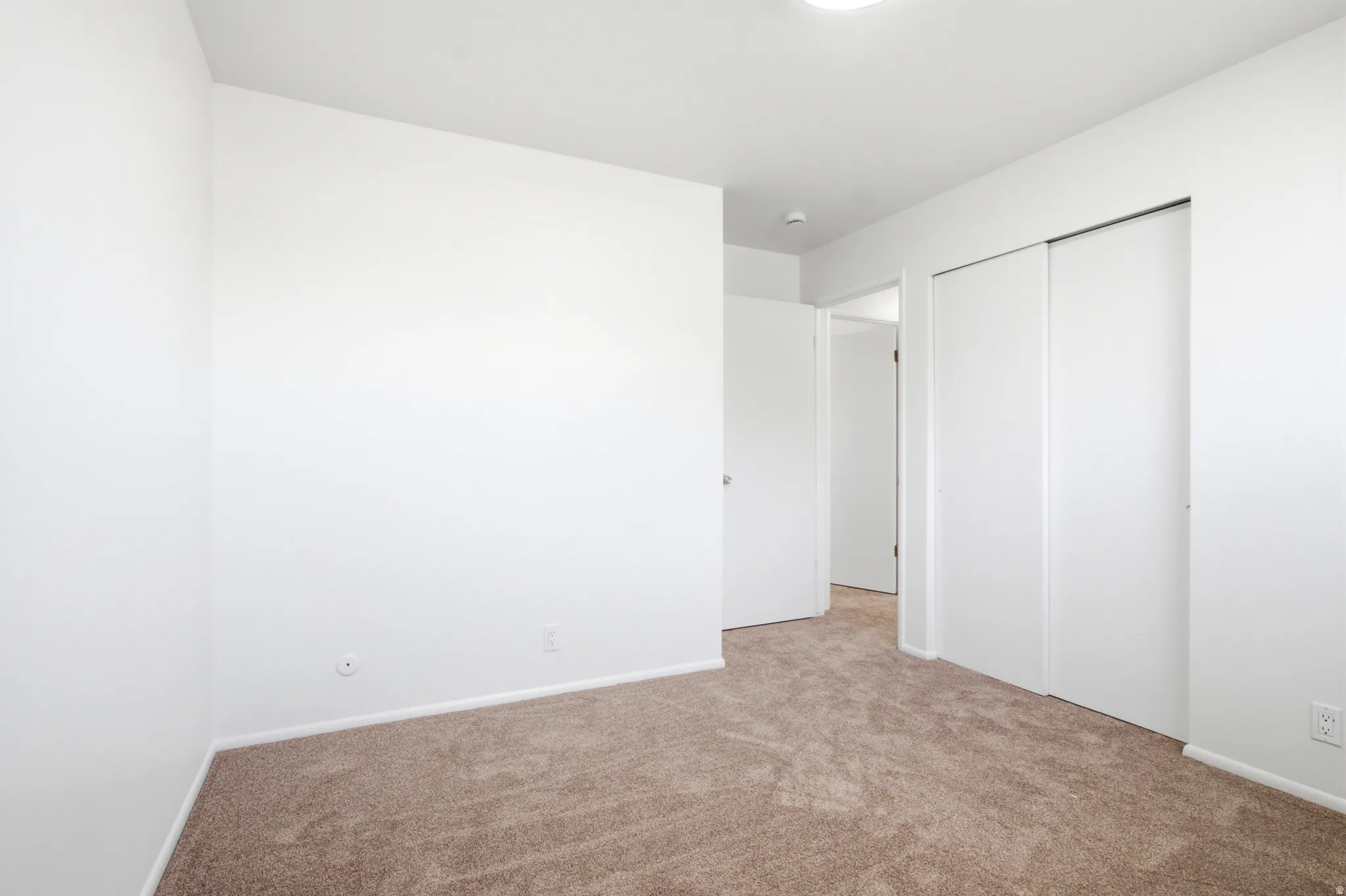 Carpeted room featuring white walls, white baseboards, and a flush-mount ceiling light