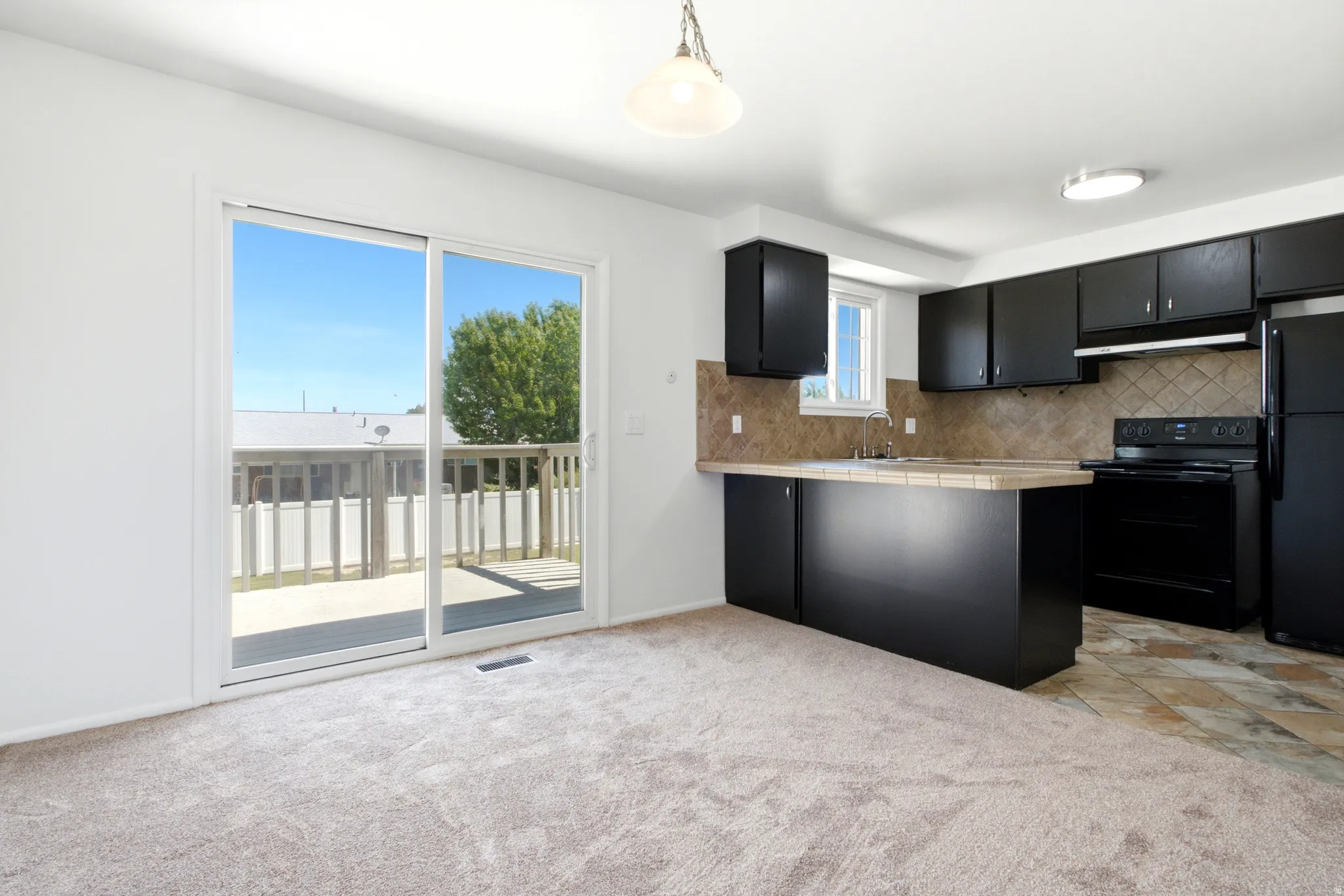 Kitchen space with black cabinetry, tiled countertops, and a full suite of black appliances