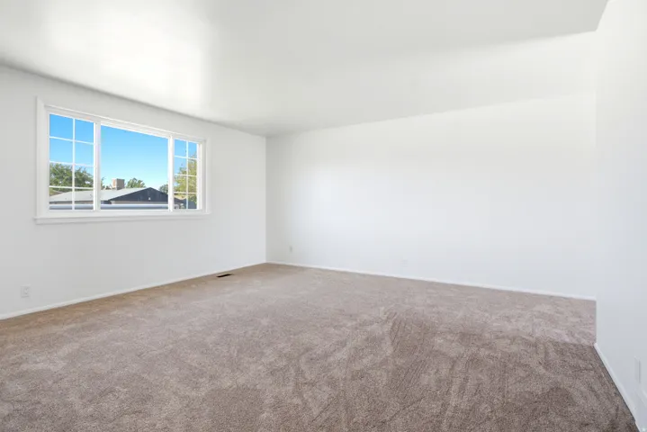 Spacious interior room featuring light brown carpeting and crisp white walls