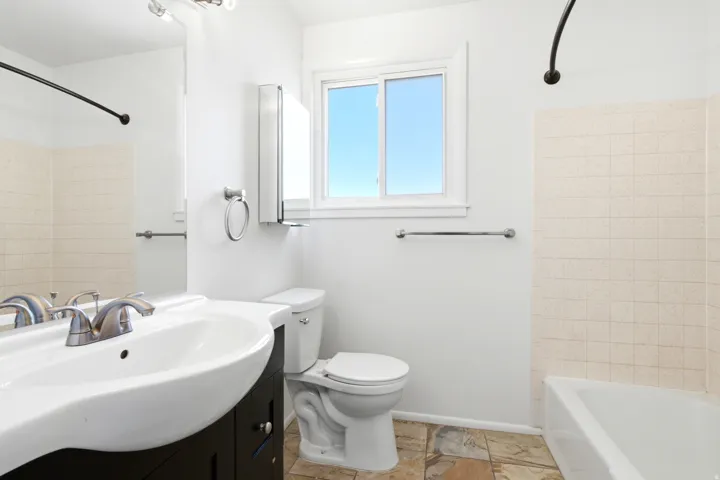 Bathroom featuring a white vanity with integrated sink, chrome faucet, and a large wall-mounted mirror