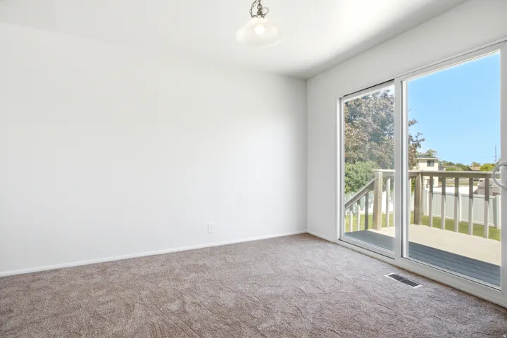 Sliding glass door opening to an exterior wood deck with a slatted railing