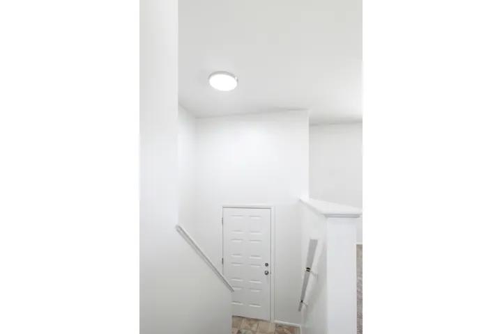 Stairwell featuring light-colored flooring, white walls, and a matching white door with a paneled design
