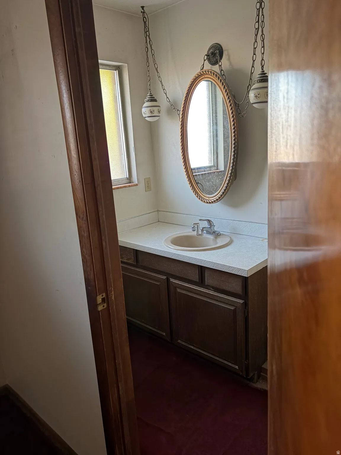 Vanity with integrated sink, wall-mounted mirror, and decorative pendant light fixtures
