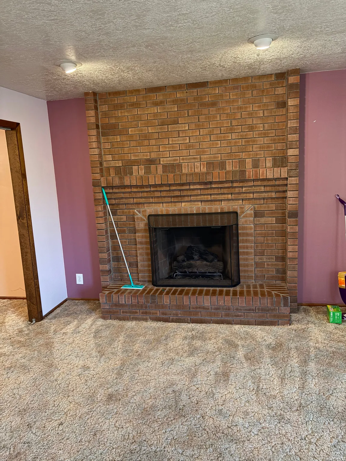 Brick fireplace with a raised hearth, metal firebox, and a hearth extension