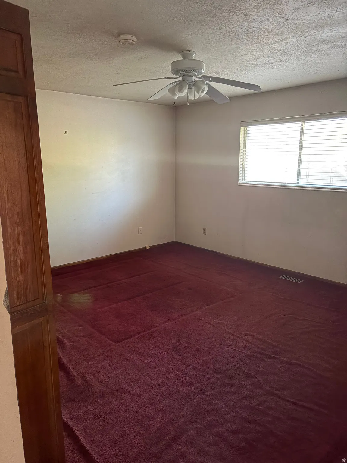 Room featuring red carpeting, a window with blinds, and a ceiling fan with integrated lighting