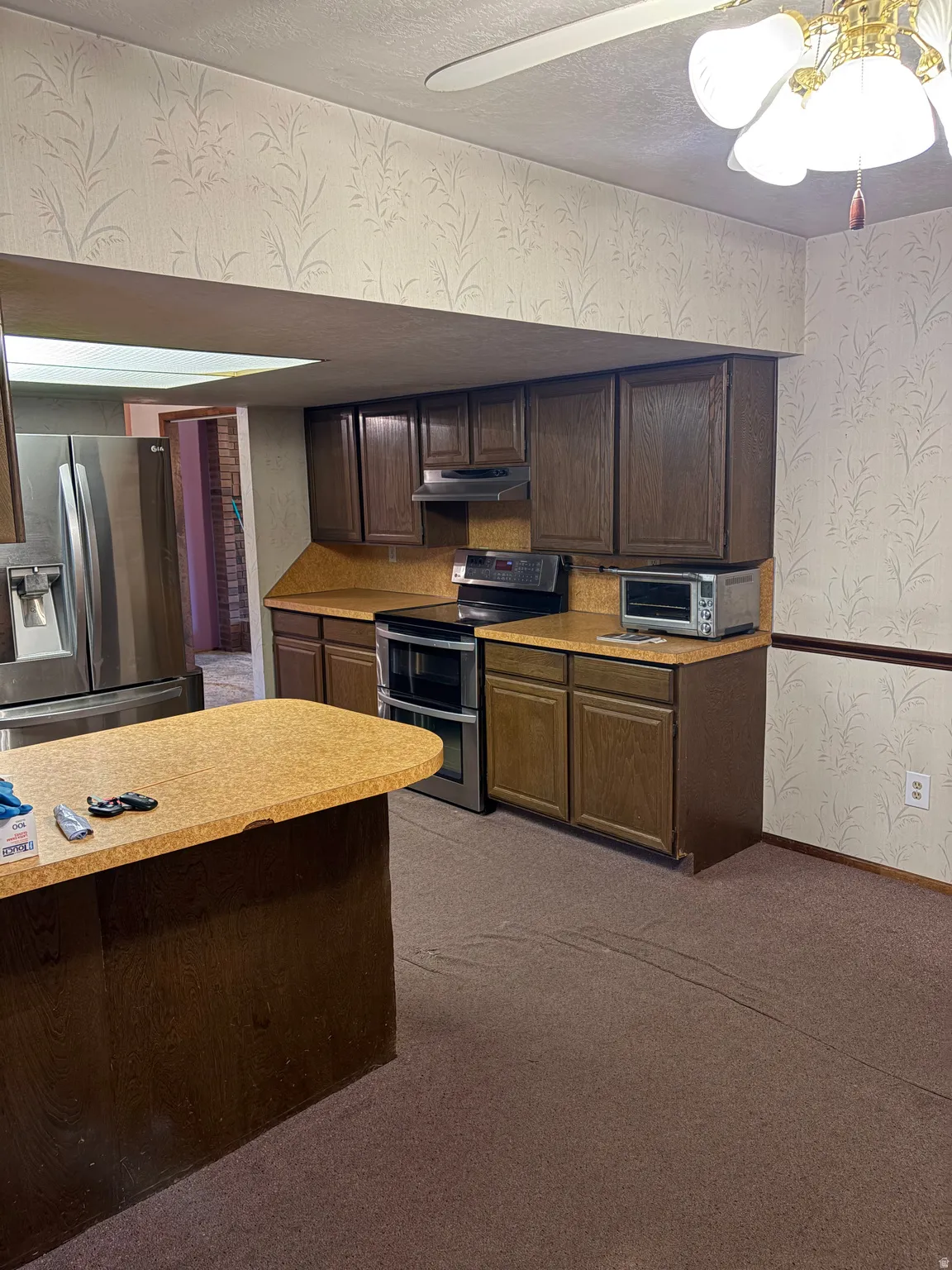Kitchen featuring wood-finish cabinetry, stainless steel appliances, and a central island with a solid surface countertop