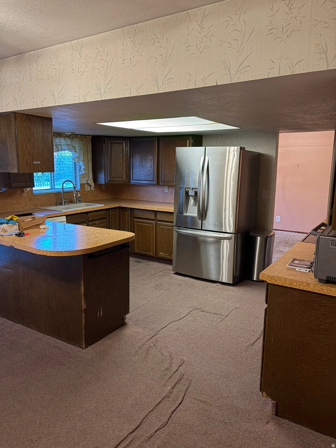Kitchen featuring a stainless steel French door refrigerator, wood cabinetry, and a built-in sink