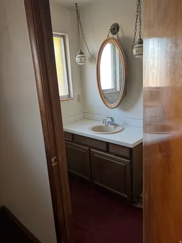 Vanity with integrated sink, wall-mounted mirror, and decorative pendant light fixtures